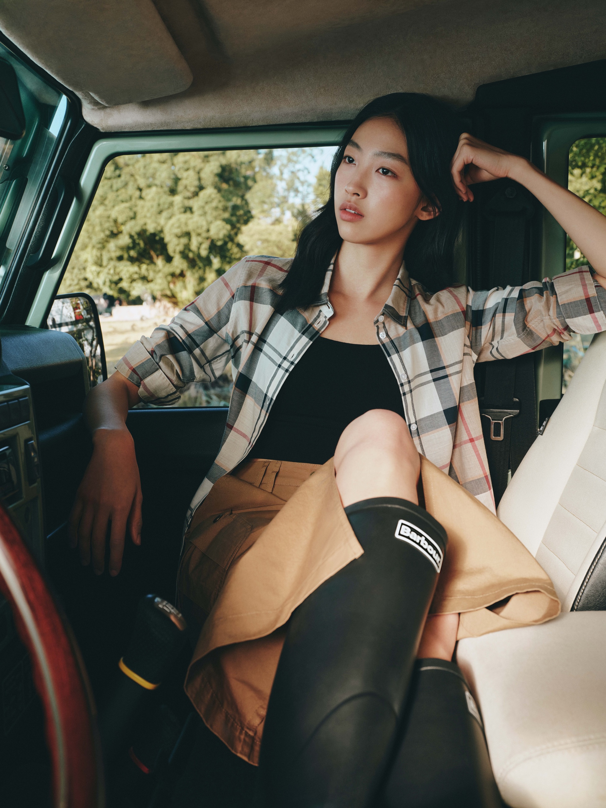 Barbour SS26 woman wearing a tartan shirt in a vehicle