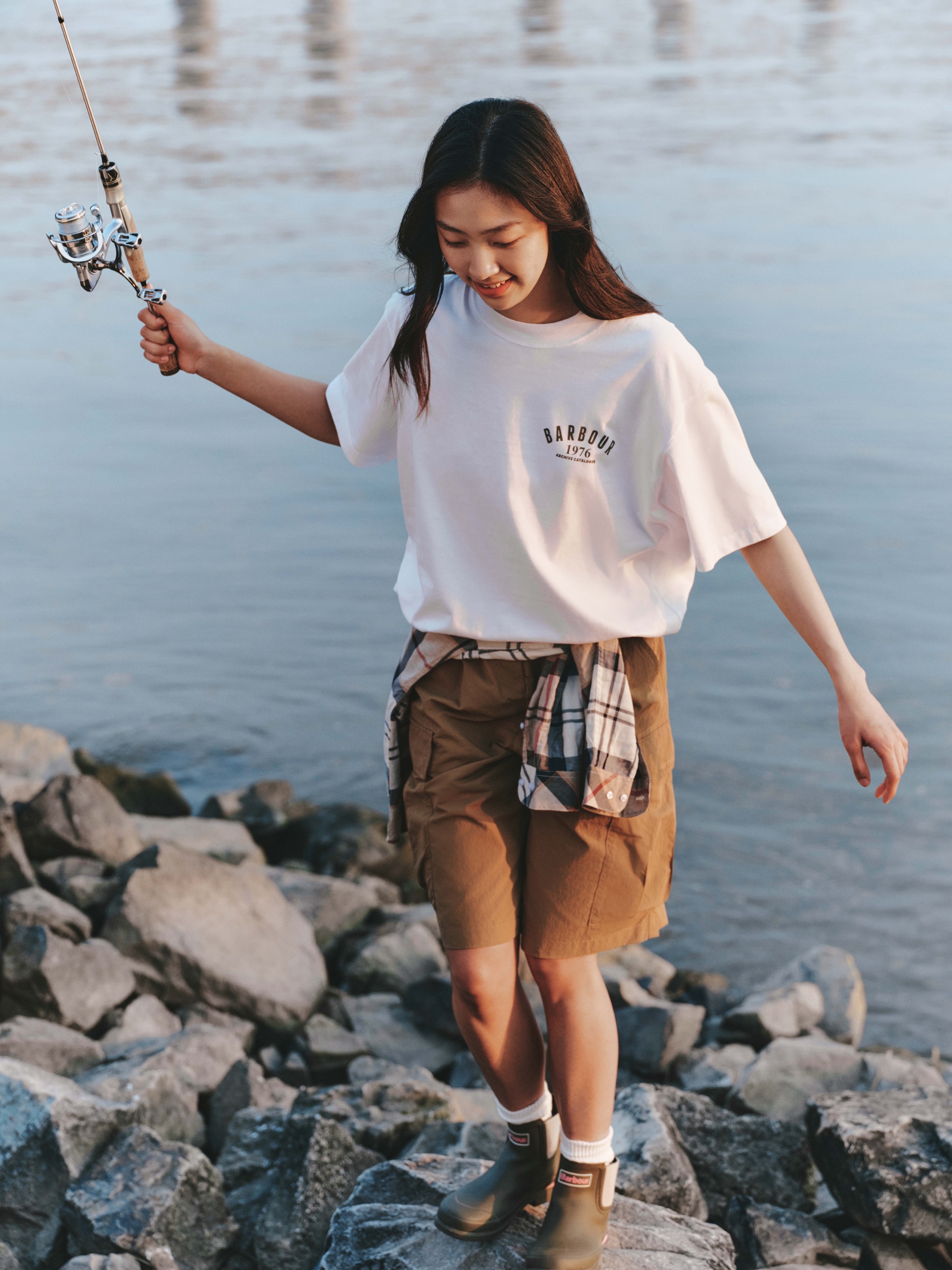 Barbour SS26 woman fishing by the water