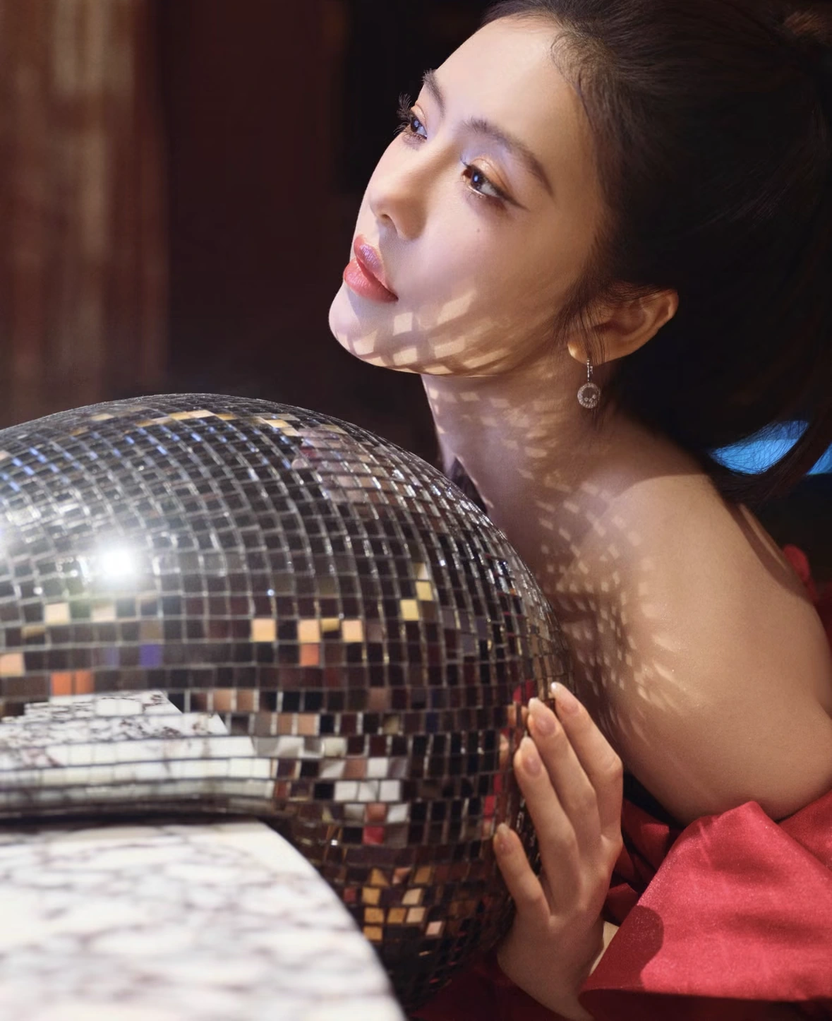 Portrait with a mirrored disco ball casting light across the face