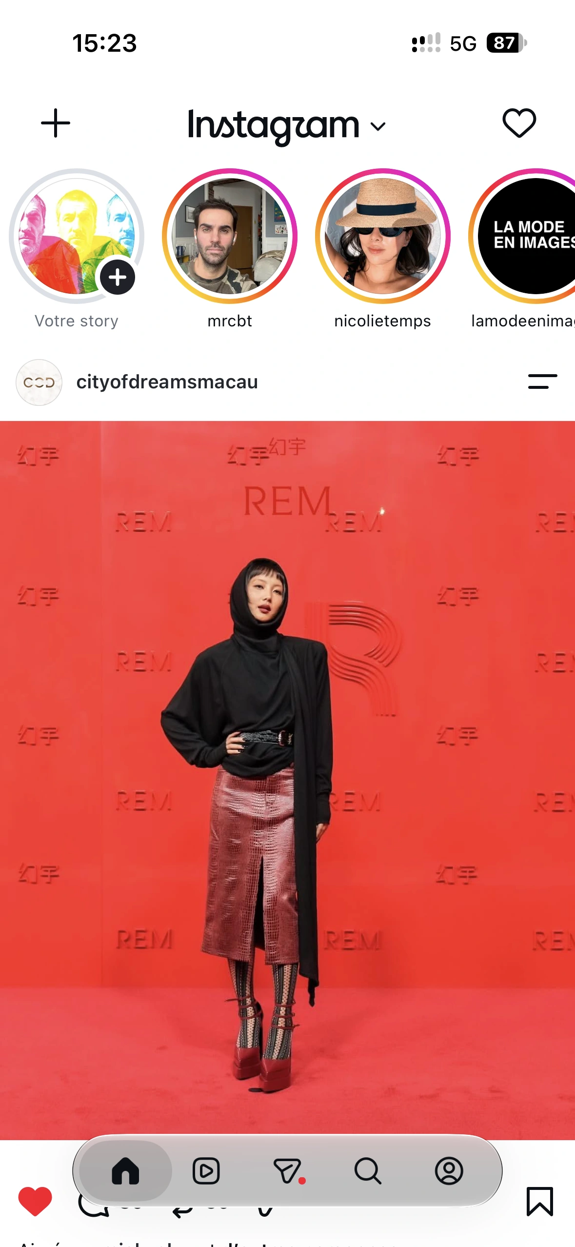 A guest in a black hooded look and metallic pink skirt on the red carpet