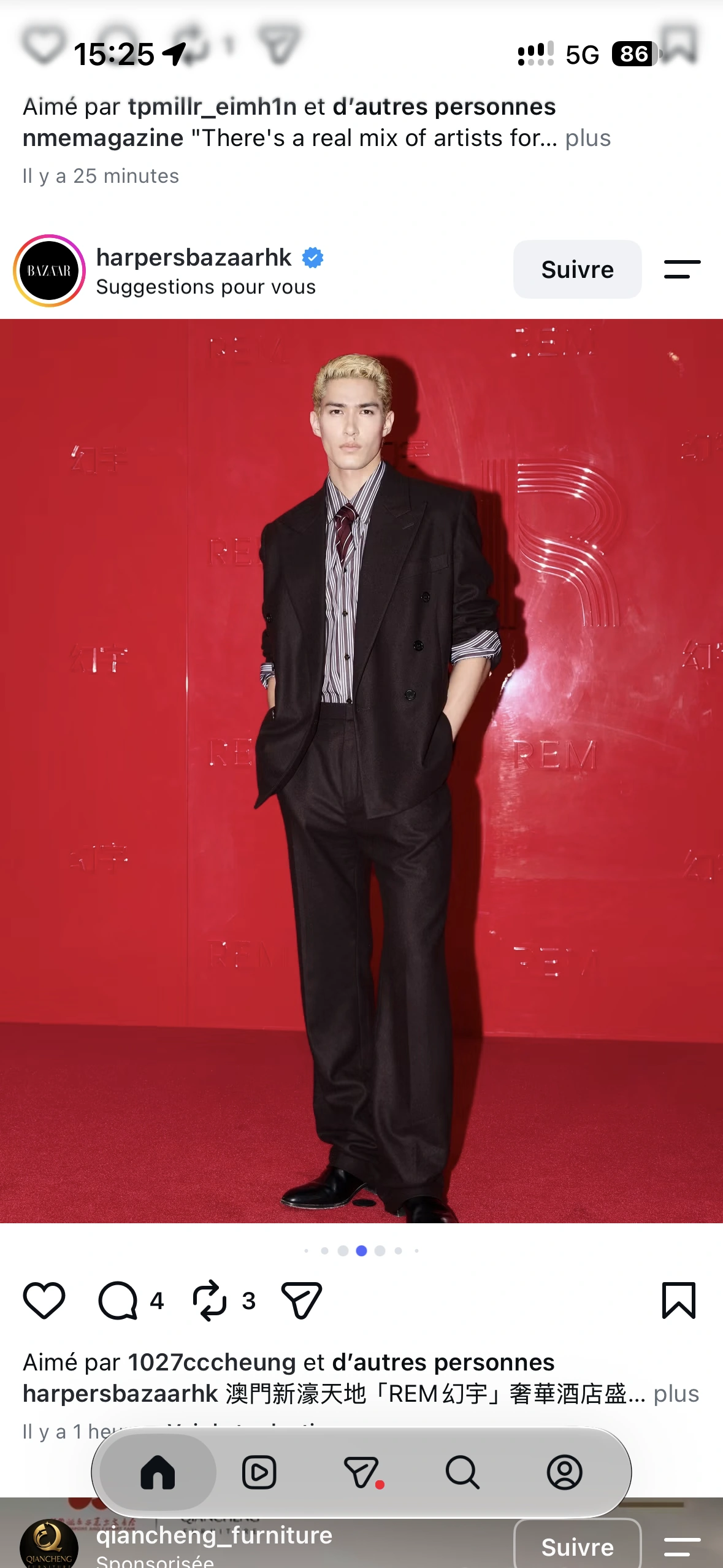 A guest in a black suit and striped shirt at the glossy red arrival backdrop