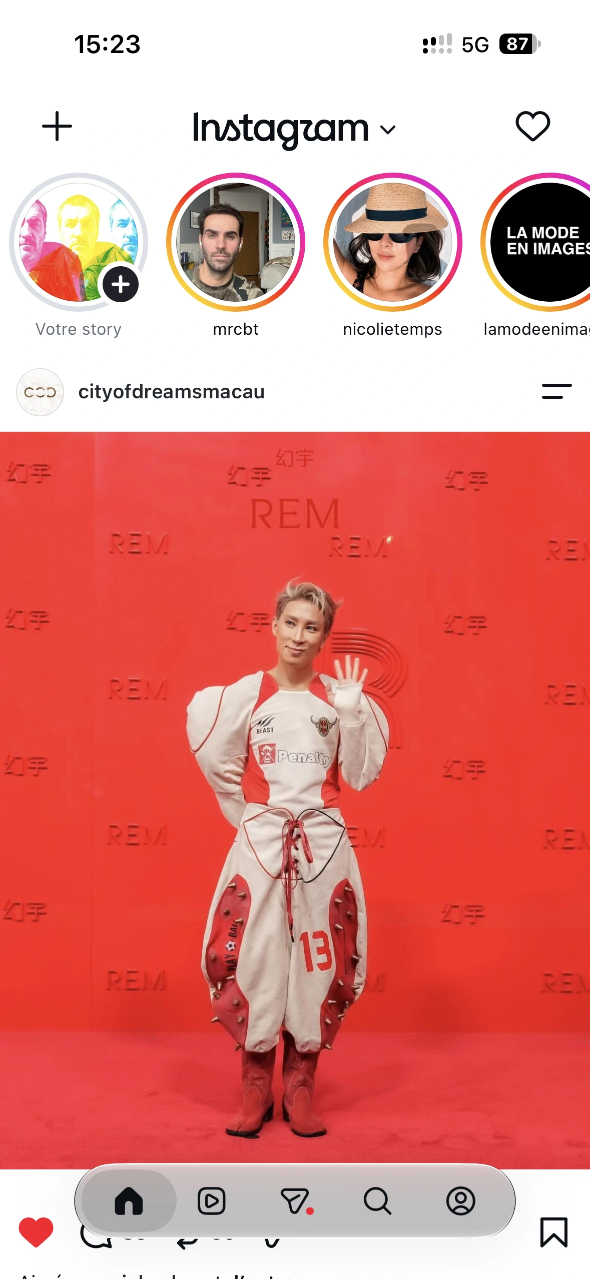 A guest in a white and red sculptural outfit waving on the red carpet